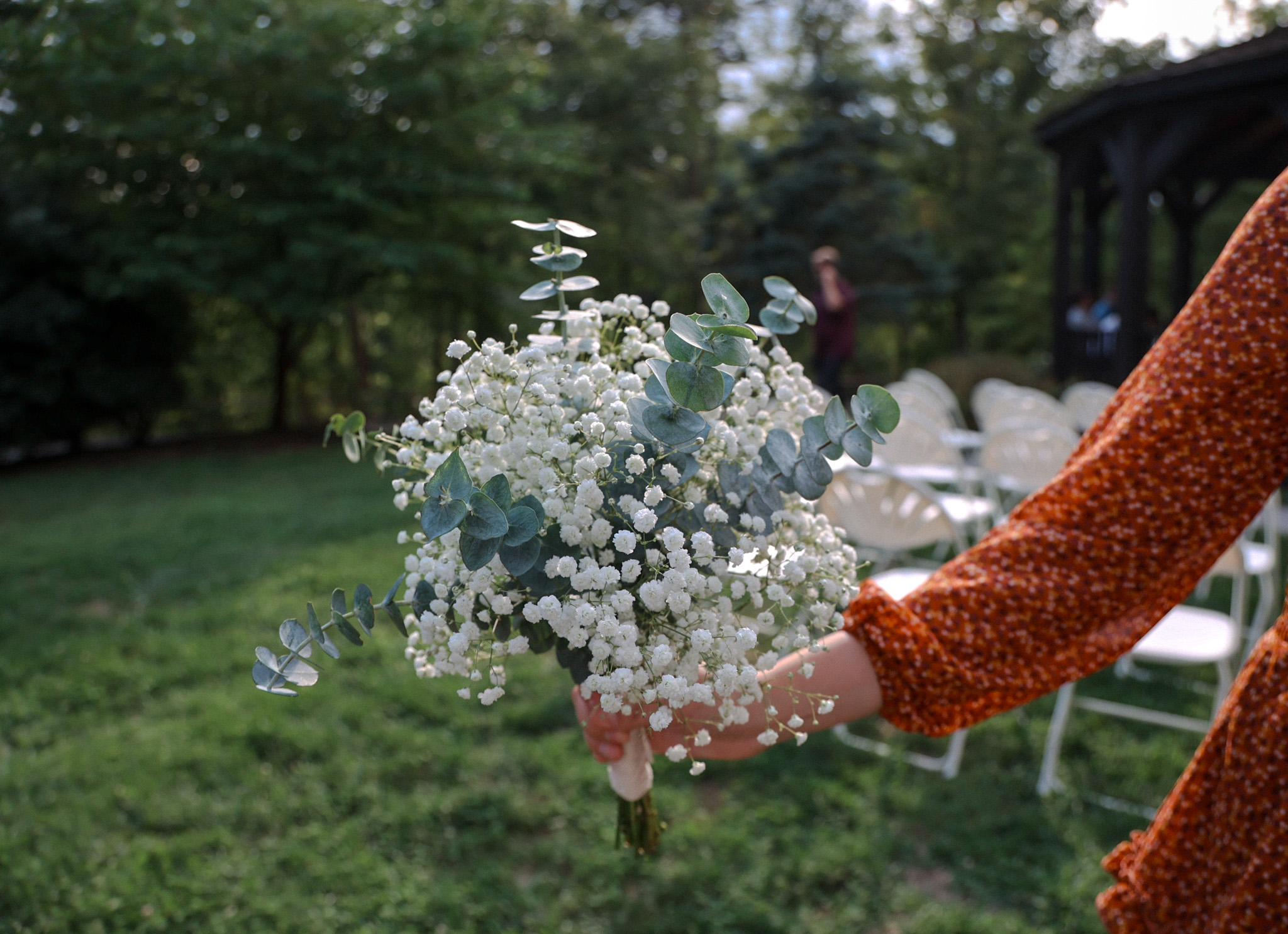 Hand holding baby's breath and eucalyptus bouquet at outdoor wedding ceremony