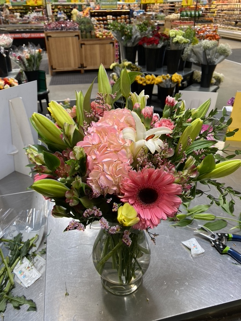 Pink hydrangea, gerbera daisy and lilies in glass vase at floral shop counter