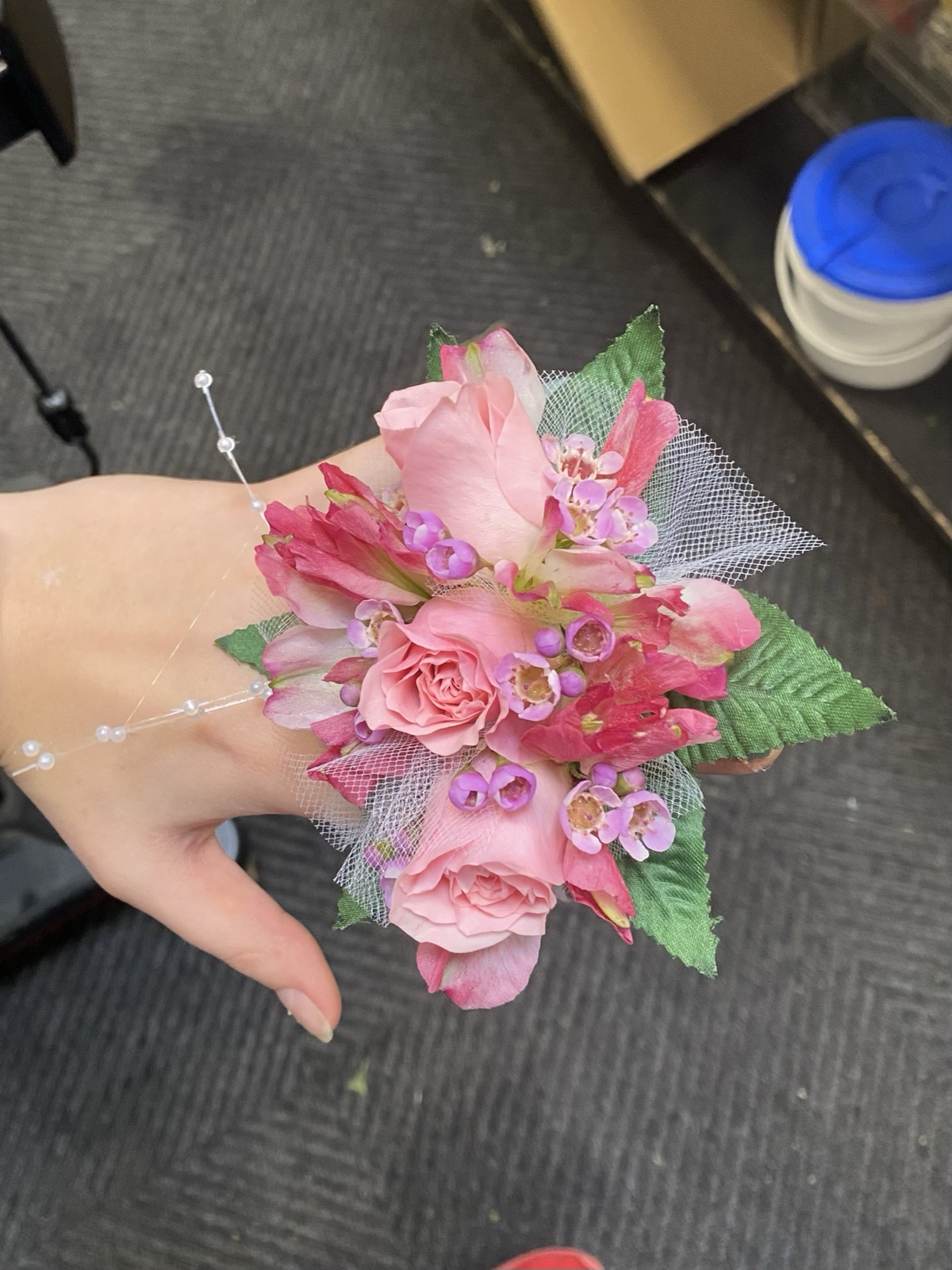 Pink rose and alstroemeria wrist corsage with tulle, held in hand