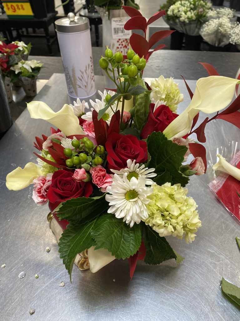 Red roses, white daisies, cream callas and green hydrangea on florist worktable