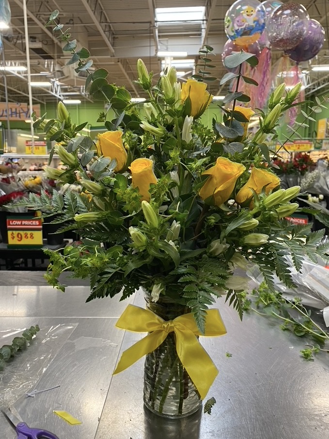 Tall vase of yellow roses and lilies with greenery, finished with yellow bow